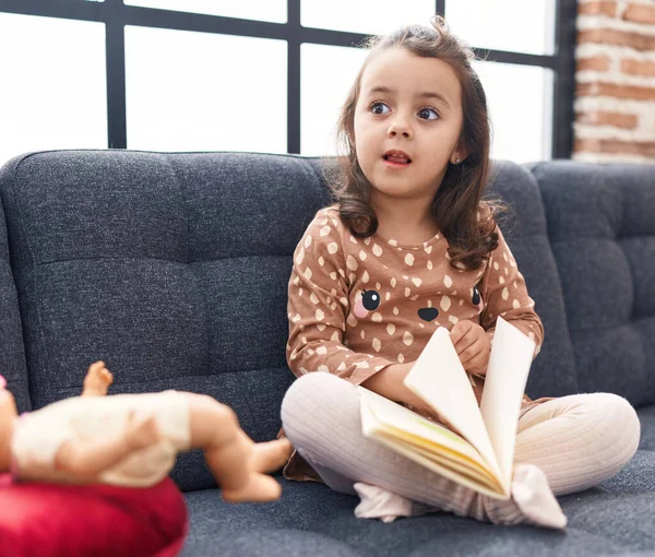 Adorable Hispanic Girl Reading Book Sitting Sofa Home — Stok fotoğraf