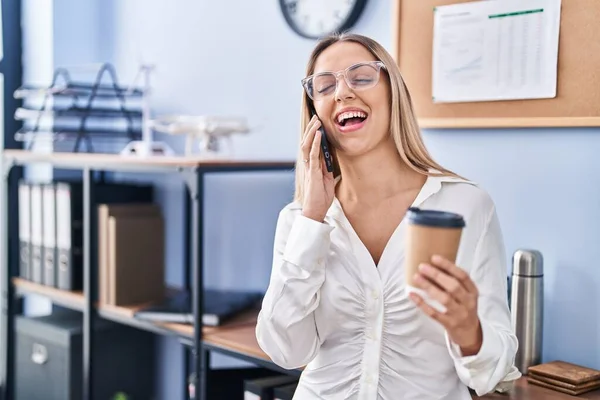 若い女性ビジネスマンがオフィスでスマートフォンのコーヒーを飲む話 — ストック写真