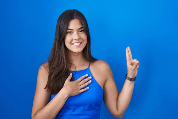 Hispanic Woman Standing Blue Background Smiling Swearing Hand Chest Fingers — Stockfoto