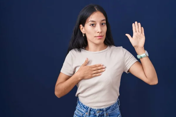 Mujer Hispana Joven Pie Sobre Fondo Azul Jurando Con Mano —  Fotos de Stock