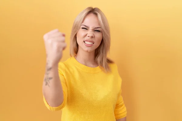 Young Caucasian Woman Wearing Yellow Sweater Angry Mad Raising Fist — 스톡 사진