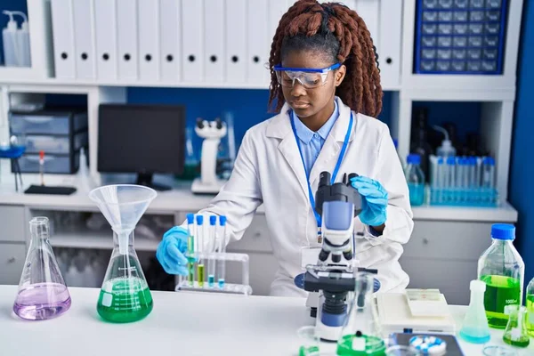 アフリカ系アメリカ人女性科学者が実験室で顕微鏡保持試験管を使って — ストック写真