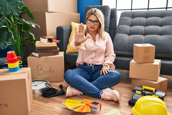 Young Hispanic Woman Moving New Home Sitting Floor Doing Stop —  Fotos de Stock