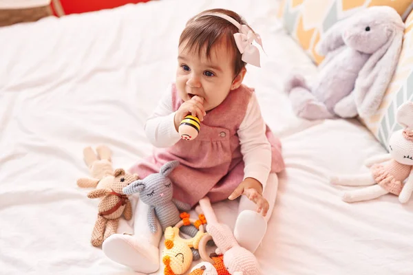 愛らしいHispanic赤ん坊Bitting Maraca座っています上のベッドルームで — ストック写真