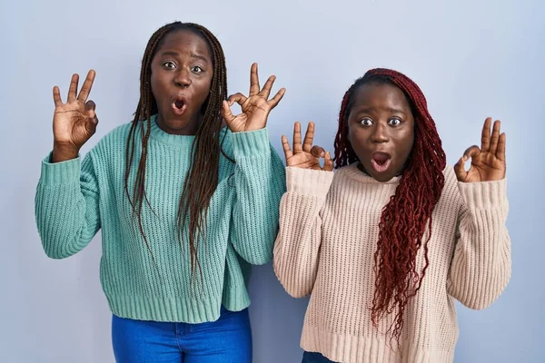 Две Африканские Женщины Стоящие Голубом Фоне Удивленно Шокированно Делают Пальцами — стоковое фото