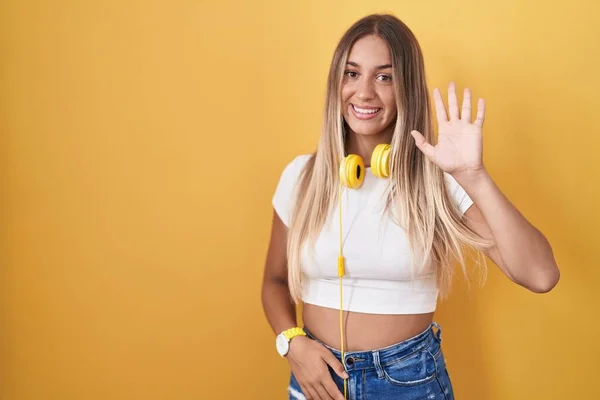 Young Blonde Woman Standing Yellow Background Wearing Headphones Waiving Saying — Stockfoto