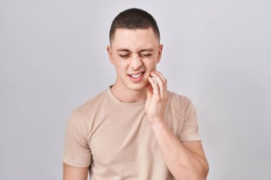 Young man standing over isolated background touching mouth with hand with painful expression because of toothache or dental illness on teeth. dentist 