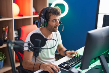 Genç İspanyol asıllı adam müzik stüdyosunda bilgisayar kullanarak video oyunu oynuyor.