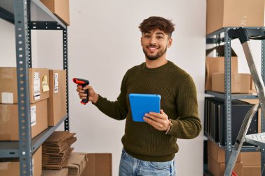 Young arab man ecommerce business worker scanning package at office