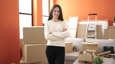 Young beautiful hispanic woman smiling confident standing with arms crossed gesture at new home