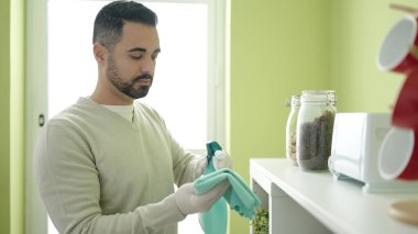 Young hispanic man cleaning toaster at home