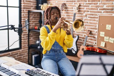 Afrikalı Amerikalı kadın müzisyen müzik stüdyosunda trompet çalıyor.