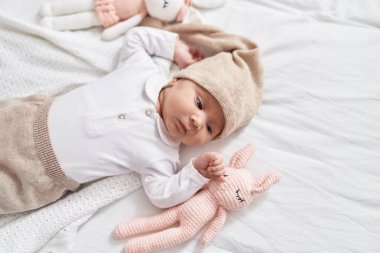 Adorable hispanic baby lying on bed at bedroom