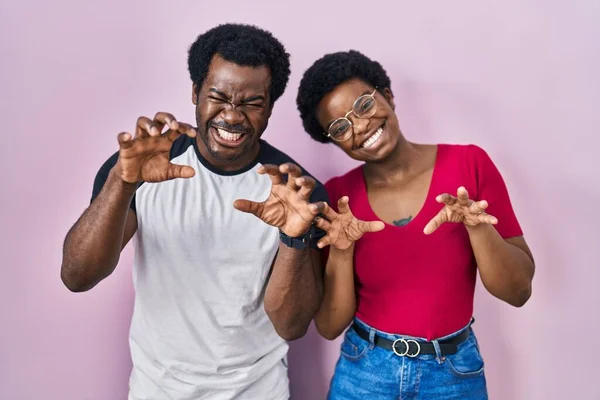 一对年轻的非洲裔美国夫妇站在粉红的背景上笑着做爪子动作 像猫一样 咄咄逼人 又性感 — 图库照片