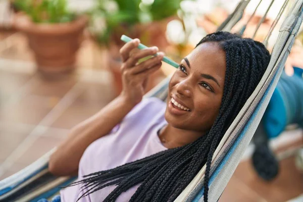 African American Woman Listening Audio Message Smartphone Lying Hammock Home — Fotografia de Stock