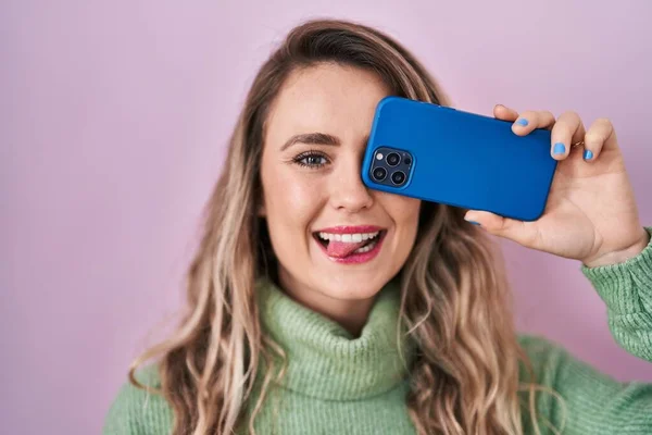 Young Caucasian Woman Covering Eye Smartphone Sticking Tongue Out Happy —  Fotos de Stock