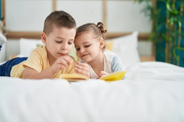 Stock image Two kids reading story book lying on bed at bedroom