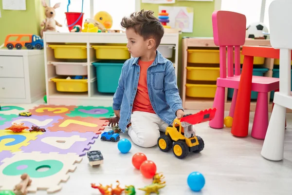 愛らしいパニック幼児遊びますともにトラクターおもちゃ座っています床に幼稚園 — ストック写真
