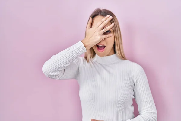 Jonge Blonde Vrouw Draagt Witte Trui Roze Achtergrond Gluuren Shock — Stockfoto