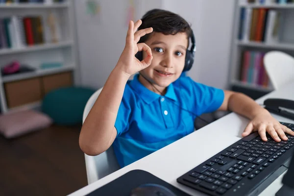 在学校里 他的小男孩用电脑笔记本电脑用手指做着 的手势 微笑着表示友善的手势 展示着极好的象征 — 图库照片