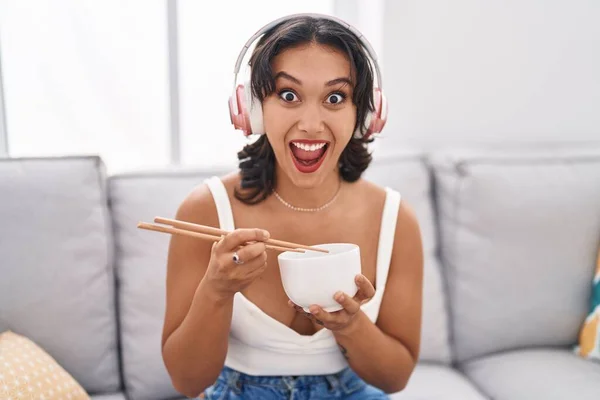 Young Hispanic Woman Eating Asian Food Using Chopsticks Celebrating Crazy — Stockfoto