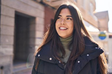 Young beautiful hispanic woman smiling confident looking to the side at street