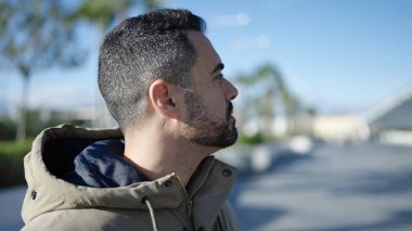 Latin kökenli genç adam ciddi bir ifadeyle sokağa bakıyor.