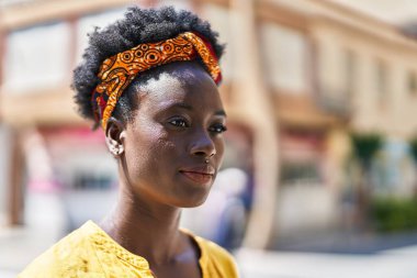 Rahat yüzü olan genç Afro-Amerikalı kadın sokakta dikiliyor.