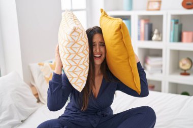 Young beautiful hispanic woman covering ears for noise at bedroom