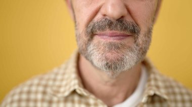 Middle age man with serious expression over isolated yellow background