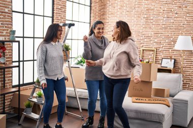 Three woman smiling confident dancing together at new home