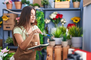 Çiçekçide defter okuyan güzel bir İspanyol kadın.