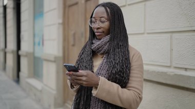 African woman smiling using smartphone at street