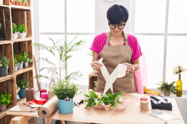 Middle age chinese woman florist make bouquet of flowers at flower shop