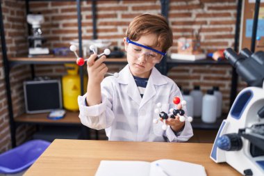 Laboratuvar sınıfında molekülleri tutan sevimli İspanyol çocuk.