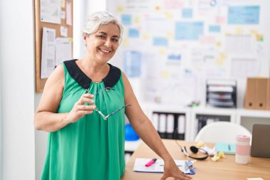 Orta yaşlı, kır saçlı, iş kadını. Ofiste kendine güvenen bir iş adamı.