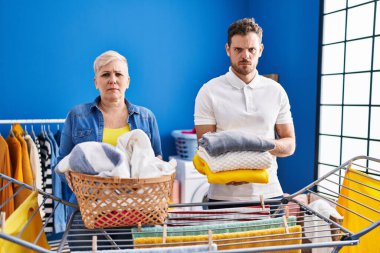 Hispanic mother and son hanging clothes at clothesline skeptic and nervous, frowning upset because of problem. negative person. 