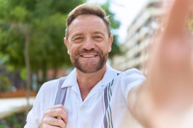 Middle age man smiling confident making selfie by camera at park