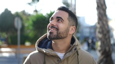 Young hispanic man smiling confident looking to the sky at park