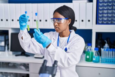 Young african american woman scientist holding test tubes at laboratory