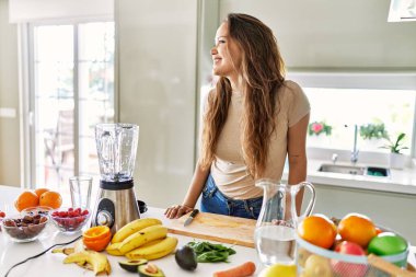 Genç, güzel İspanyol kadın mutfakta sebze suyu ve blender hazırlıyor.