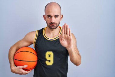 Basketbol topu tutan sakallı genç kel adam avucunun içi gibi şarkı söylemeyi kesiyor. Yüzünde olumsuz ve ciddi bir jest olan uyarı ifadesi. 