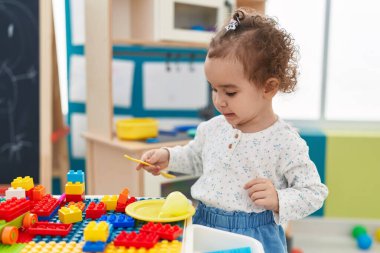 Adorable hispanic toddler playing at kindergarten