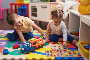 İki çocuk arabalarla oynuyor. Oyuncak ve matematik oyunu. Anaokulunun zemininde oturuyor.