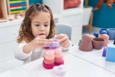 Sevimli sarışın çocuk anaokulundaki masada oyuncaklarla oynuyor.