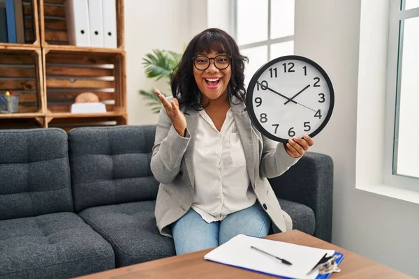 Latynoska Kobieta Pracuje Biurze Terapii Trzymając Zegar Świętując Zwycięstwo Szczęśliwym — Zdjęcie stockowe