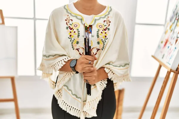 Resim stüdyosunda fırça tutan genç İspanyol kadın.