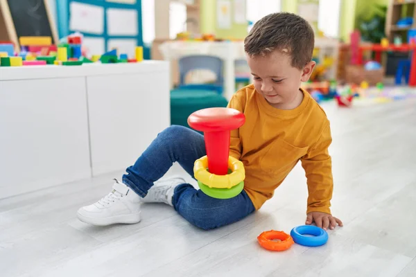 愛らしいですCaucasian男の子遊びますとともにフープおもちゃ座っています床に幼稚園 — ストック写真