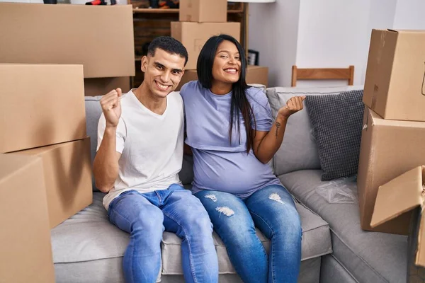 Young Hispanic Couple Expecting Baby Sitting Sofa New Home Screaming — Stock Photo, Image