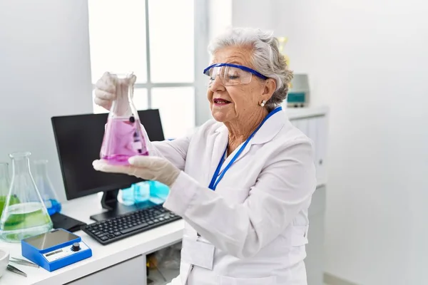 研究室で科学者の制服保持試験管を身に着けているシニア白髪の女性 — ストック写真